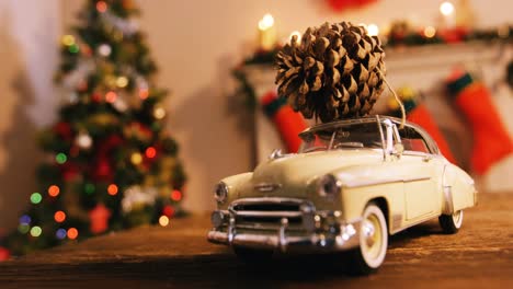 Toy-car-with-pine-cone-on-wooden-table