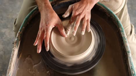 Mid-section-of-potter-making-pot