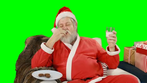 Papá-Noel-Relajándose-En-El-Sofá-Y-Comiendo-Comida-Dulce