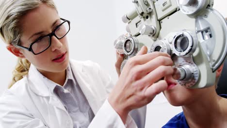 Female-optometrist-examining-young-patient-on-chiropter