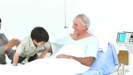 Grandson-and-father-visiting-a-senior-man-recovering-in-hospital