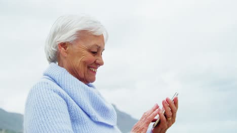 Senior-woman-using-mobile-phone-on-beach