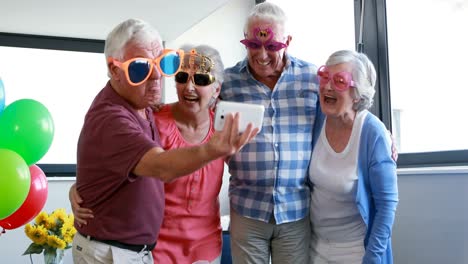 Senior-citizens-taking-selfie-on-mobile-phone-during-birthday-party