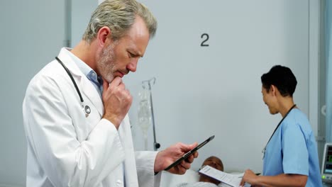 Doctor-using-digital-tablet-while-nurse-interacting-with-patient