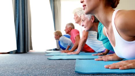 Trainer-assisting-senior-citizens-in-practicing-yoga