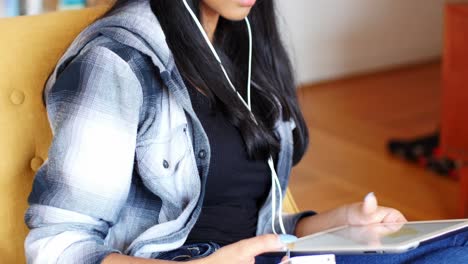 Woman-listening-to-music-with-headphones-from-her-digital-tablet