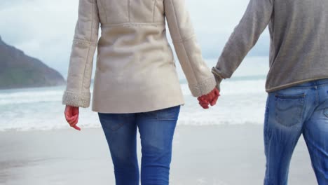 Couple-holding-hands-and-walking-on-beach