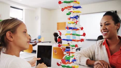 Teacher-assisting-schoolgirl-with-molecule-model-in-classroom