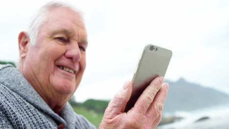 Senior-man-using-mobile-phone-on-beach