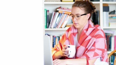 Mujer-Usando-Una-Computadora-Portátil-Mientras-Toma-Una-Taza-De-Café