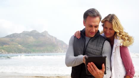 Couple-using-digital-tablet-on-beach