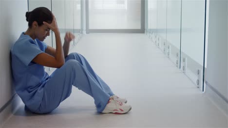 Sad-female-surgeon-sitting-in-corridor