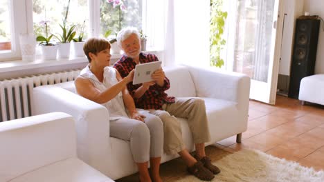 Älteres-Paar-Nutzt-Digitales-Tablet-Im-Wohnzimmer
