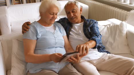Senior-couple-looking-at-a-photo-album-in-living-room