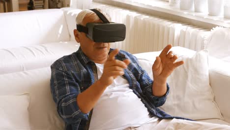 Senior-man-using-virtual-reality-headset-in-living-room