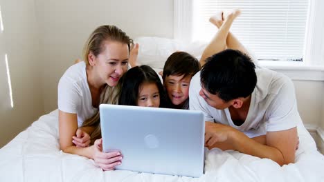 Familia-Feliz-Relajándose-En-La-Cama-Y-Usando-Una-Computadora-Portátil