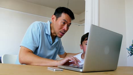 Padre-E-Hijo-Usando-Una-Computadora-Portátil-En-La-Sala-De-Estar