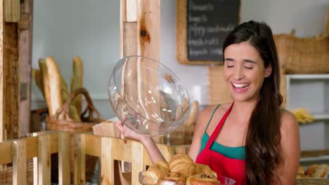 Smiling-female-staff-holding-freshly-baked-bread-covered-in-glass-cloche