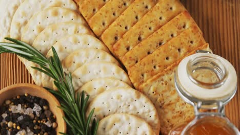Bowl-of-green-olives,-spices,-crispy-biscuits,-jam,-rosemary-herb,-cheese-and-walnuts