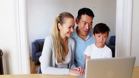 Familia-Feliz-Usando-Una-Computadora-Portátil-En-La-Sala-De-Estar
