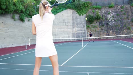 Coach-assisting-sportswoman-in-playing-tennis