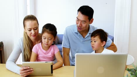 Glückliche-Familie-Mit-Digitalem-Tablet-Und-Laptop-Im-Wohnzimmer