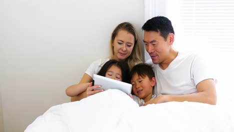 Glückliche-Familie,-Die-Sich-Im-Bett-Entspannt-Und-Ein-Digitales-Tablet-Nutzt