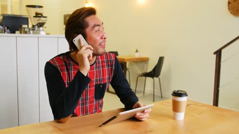 Hombre-Hablando-Por-Teléfono-Móvil-Mientras-Usa-Una-Tableta-Digital
