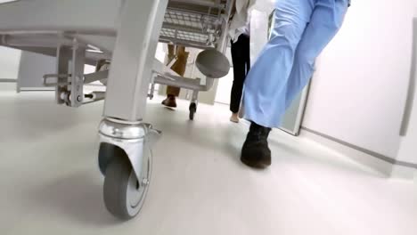 Doctor-pushing-emergency-stretcher-in-corridor