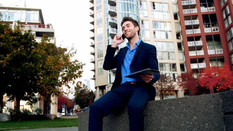 Businessman-talking-on-mobile-phone-and-holding-digital-tablet