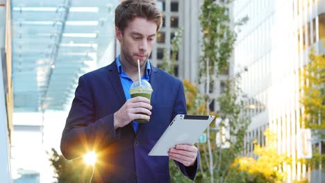 Businessman-using-digital-tablet-while-having-juice