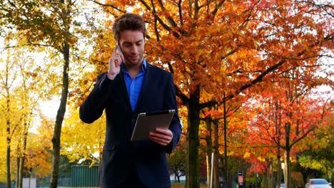 Businessman-talking-on-mobile-phone-and-holding-digital-tablet
