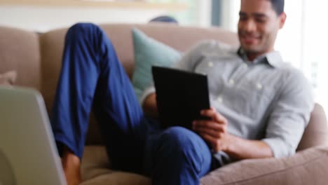 Glücklicher-Mann-Mit-Digitalem-Tablet-Im-Wohnzimmer