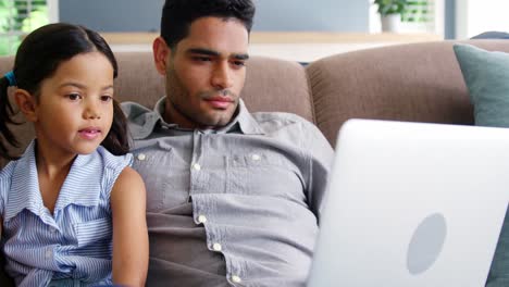 Father-and-daughter-using-laptop-in-living-room