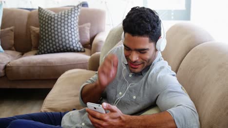 Happy-man-listening-music-on-mobile-phone-in-living-room