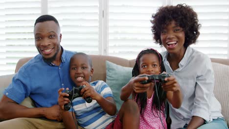 Family-sitting-on-sofa-and-playing-video-game