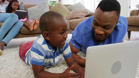 Father-and-son-using-laptop-in-living-room-