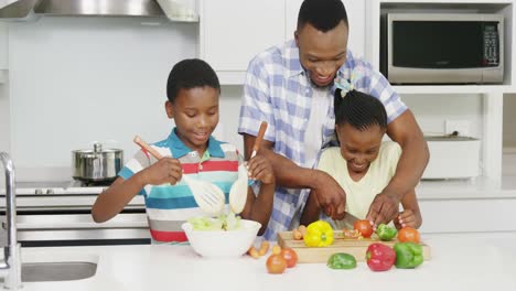 Father-and-children-preparing-vegetable-salad-in-kitchen