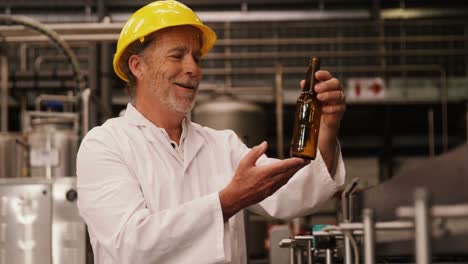 Factory-worker-inspecting-a-glass-bottle-at-bottling-plant