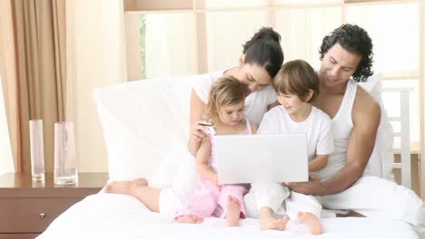 Familie-Kauft-Online-Mit-Einem-Laptop-Im-Schlafzimmer