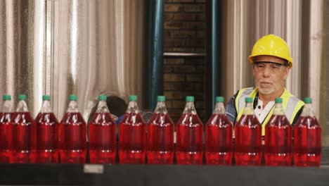 Worker-checking-juice-bottles-on-production-line