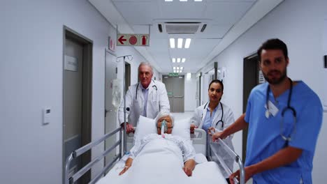 Doctors-and-nurse-pushing-emergency-stretcher-bed-in-corridor