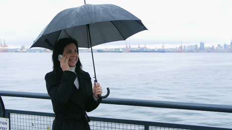 Woman-holding-umbrella-and-talking-on-mobile-phone