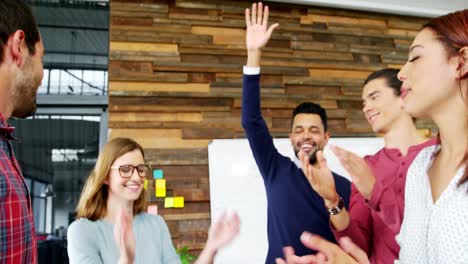 Business-executives-giving-high-fives-while-working-in-office
