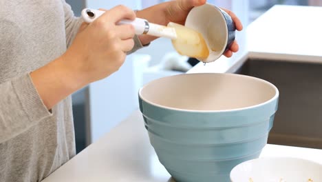 Woman-adding-ingredients-to-bowl-for-baking