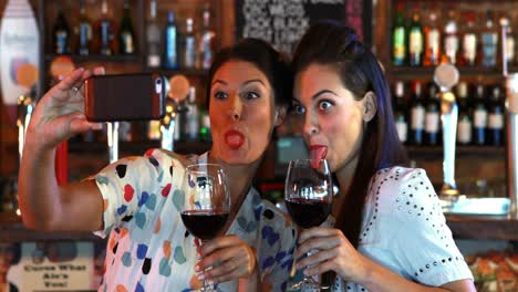 Friends-taking-selfie-on-mobile-phone-while-having-red-wine