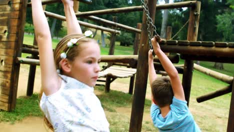 Siblings-hanging-on-a-playing-equipment-in-park