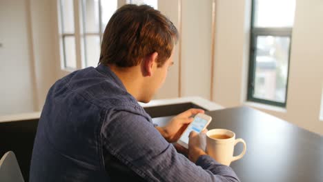 Man-using-mobile-phone-with-black-coffee-on-table