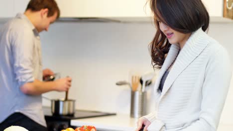 Woman-interacting-while-chopping-vegetables-in-kitchen
