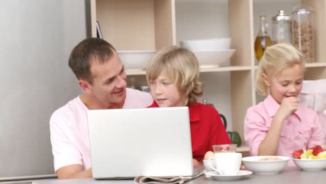Family-having-breakfast-and-using-a-laptop-in-the-kitchen